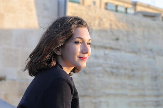 在马耳他姆加尔，一名年轻女子靠近历史悠久的石墙，在户外微笑着