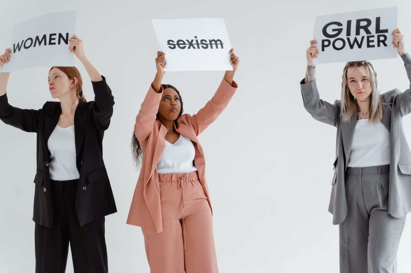 Trois femmes tiennent des pancartes contre le sexisme et pour le pouvoir d’agir des femmes