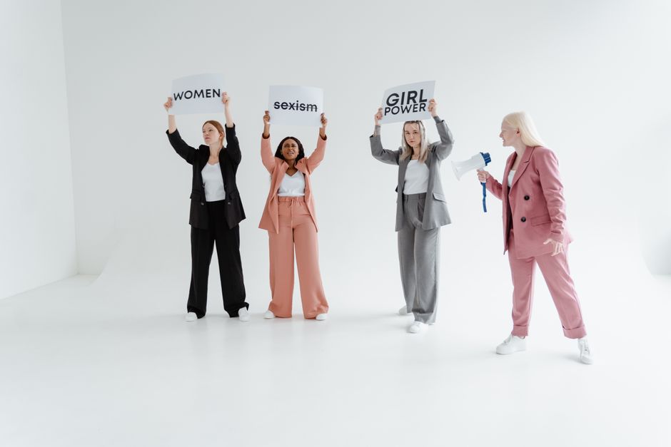 Mujeres de pie con pancartas abogando por la igualdad de género y el empoderamiento.