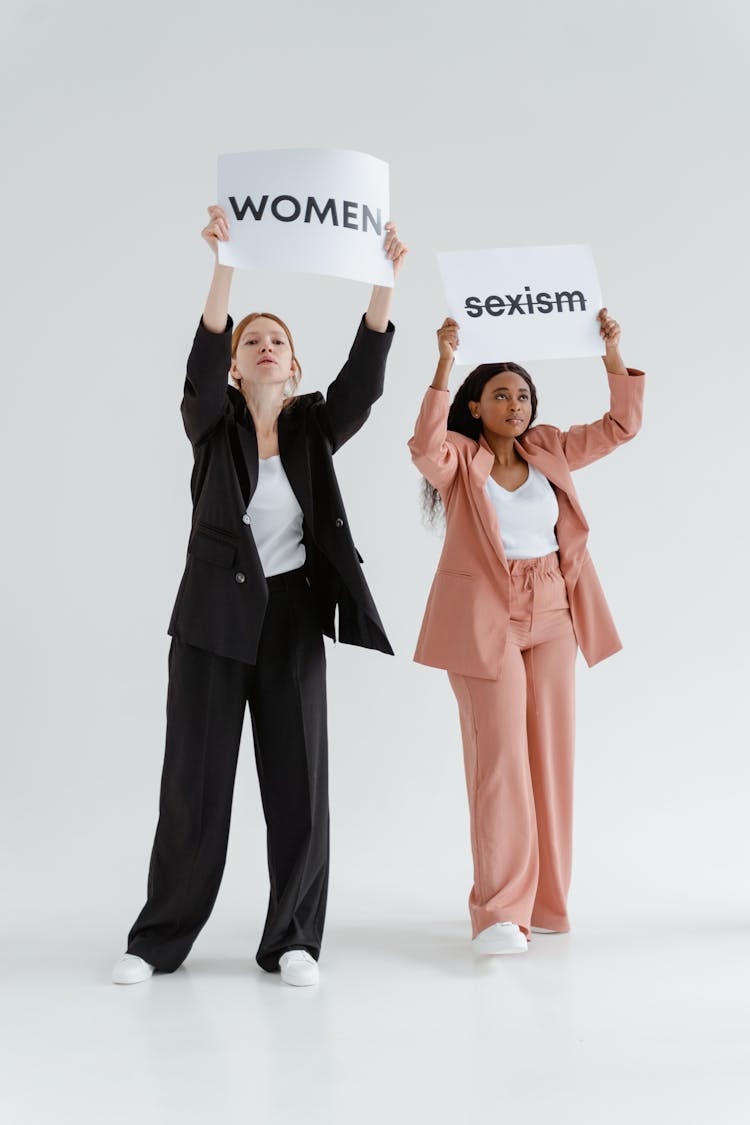 Women In Pink And Black Blazers Protesting While Holding A Placards