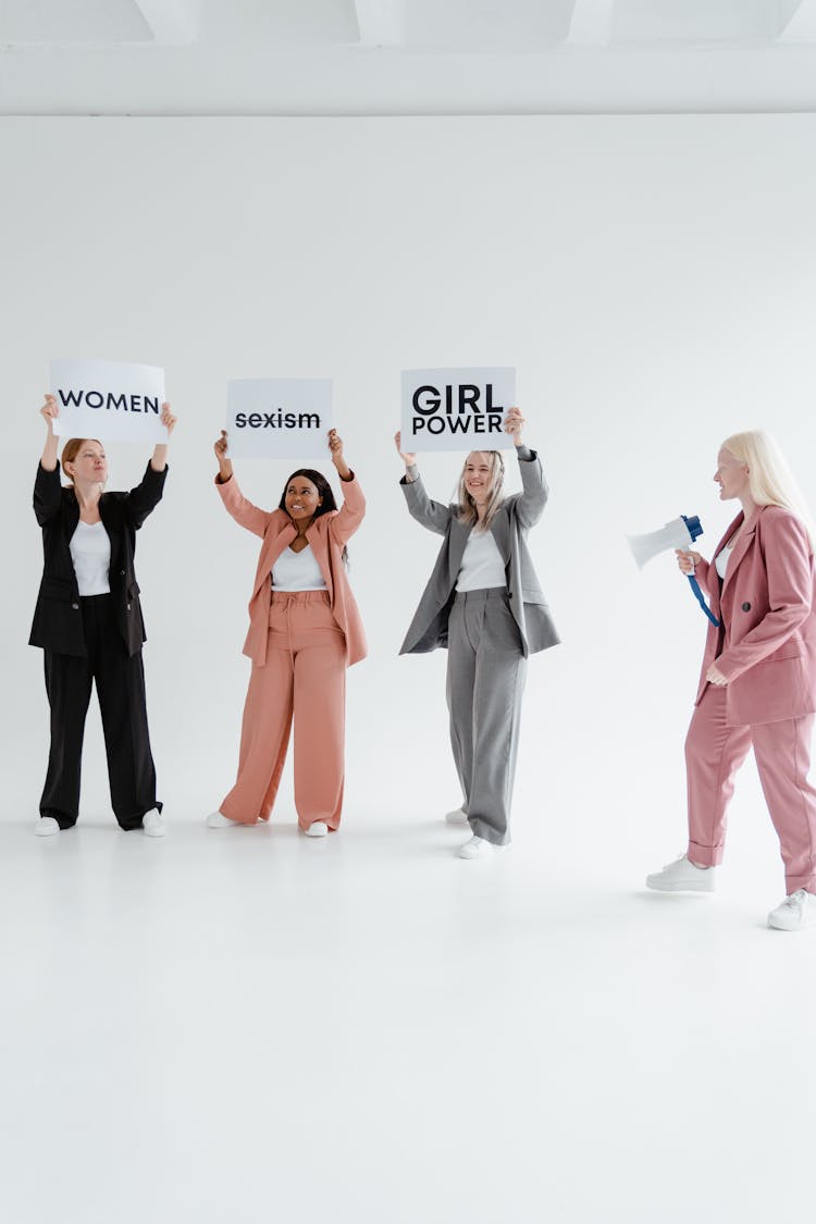 A Group Of Women Wearing Blazers And Pants Standing While Protesting