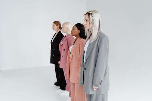 A Group of Women Standing Together while Wearing Blazers and Pants in Different Colors