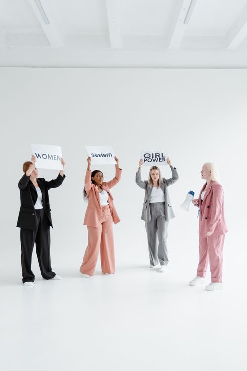 Free Group of diverse women in business attire holding signs with empowering messages against sexism. Stock Photo
