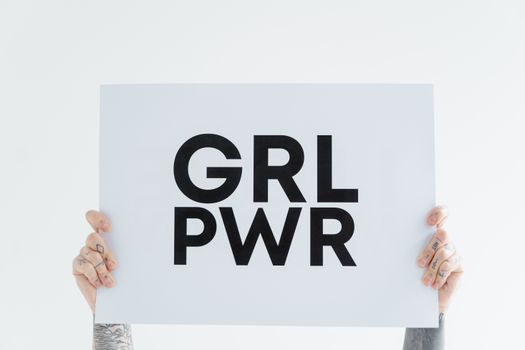 Hands holding a 'GRL PWR' sign against a white background, symbolizing empowerment.