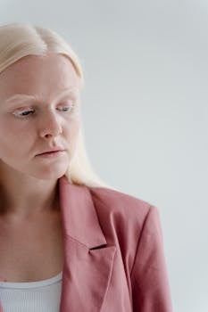 Elegant studio portrait of a blonde woman in a pink blazer with a white background.