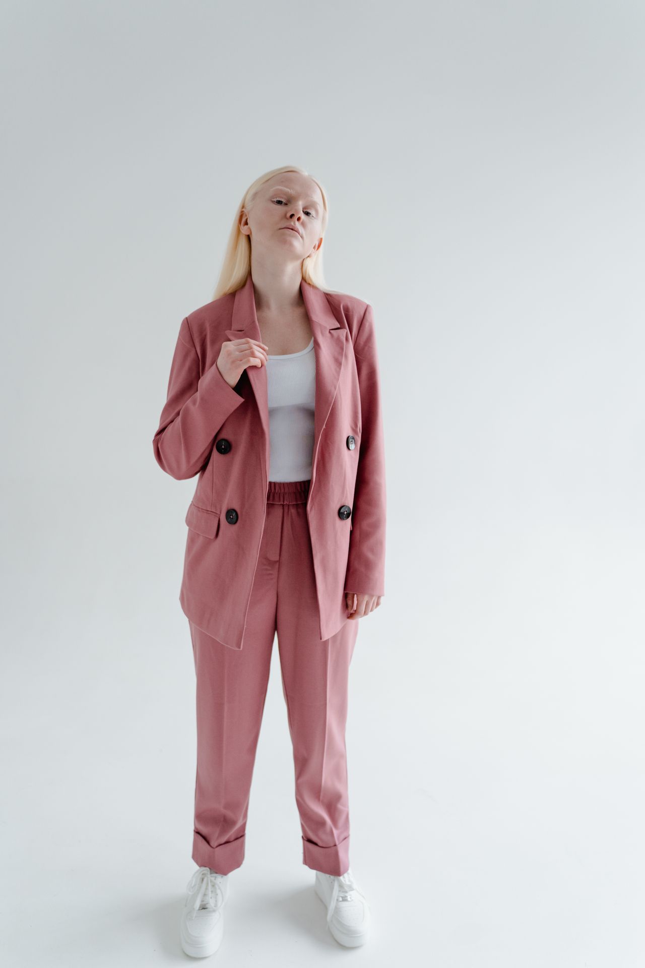 Woman in a dusty rose suit with a white top and white sneakers