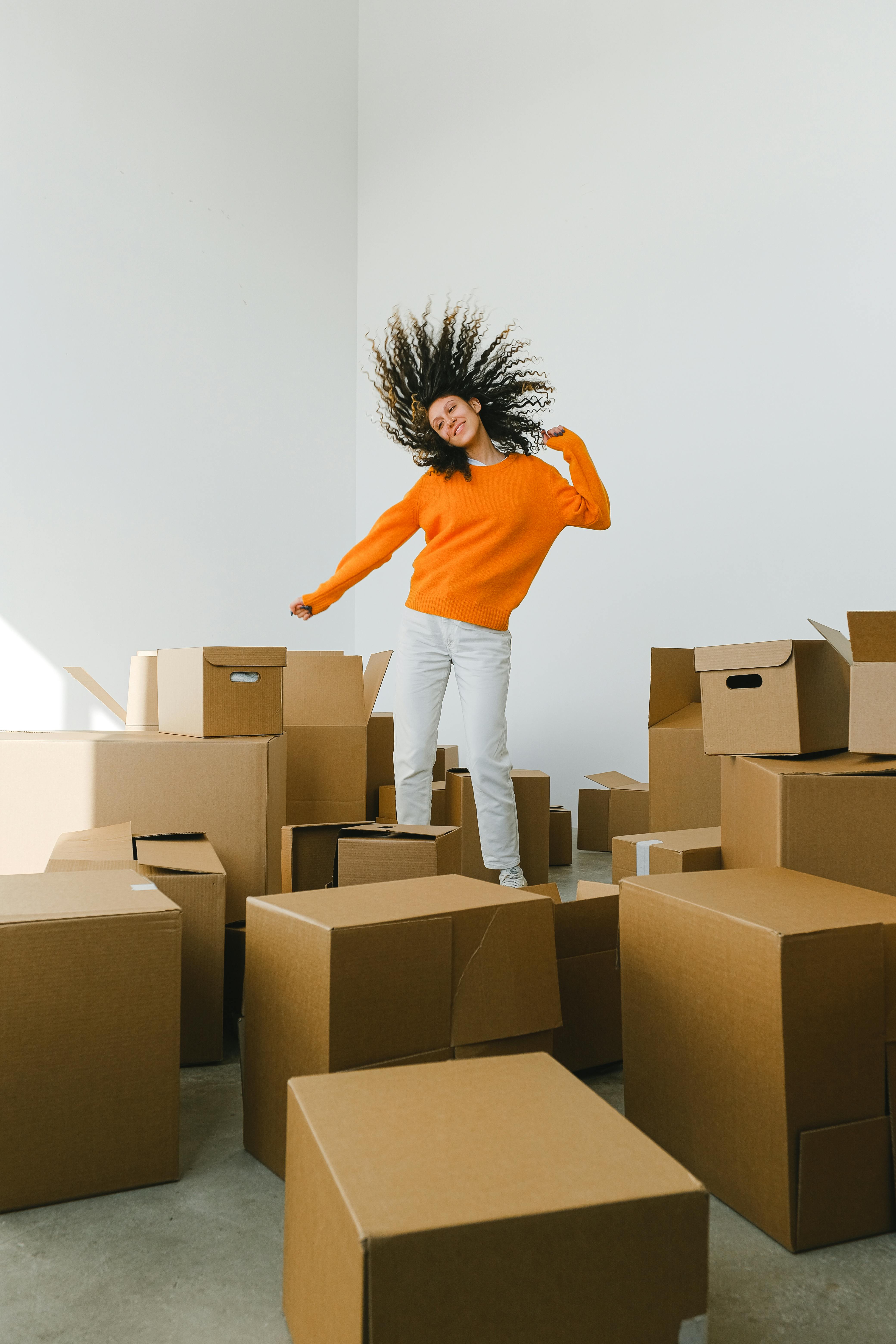 excited woman with flying hair having fun among cardboard boxes