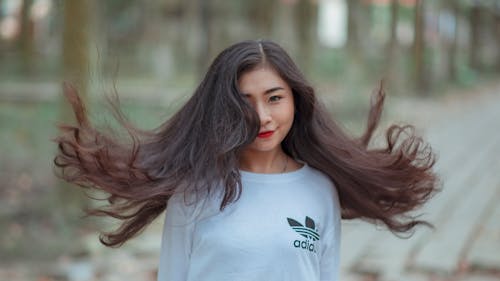 Frau Mit Langen Haaren, Die Auf Luft Winken Und Weißes Adidas Hemd Tragen