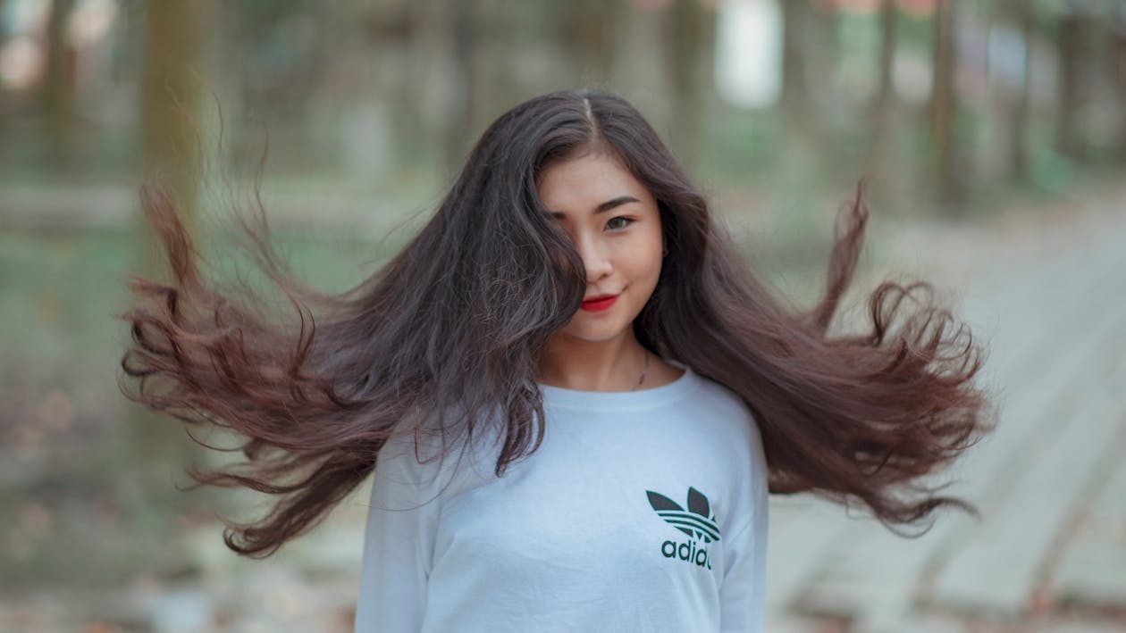 Wanita Dengan Rambut Panjang Melambai Di Udara Dan Mengenakan Kemeja Adidas Putih