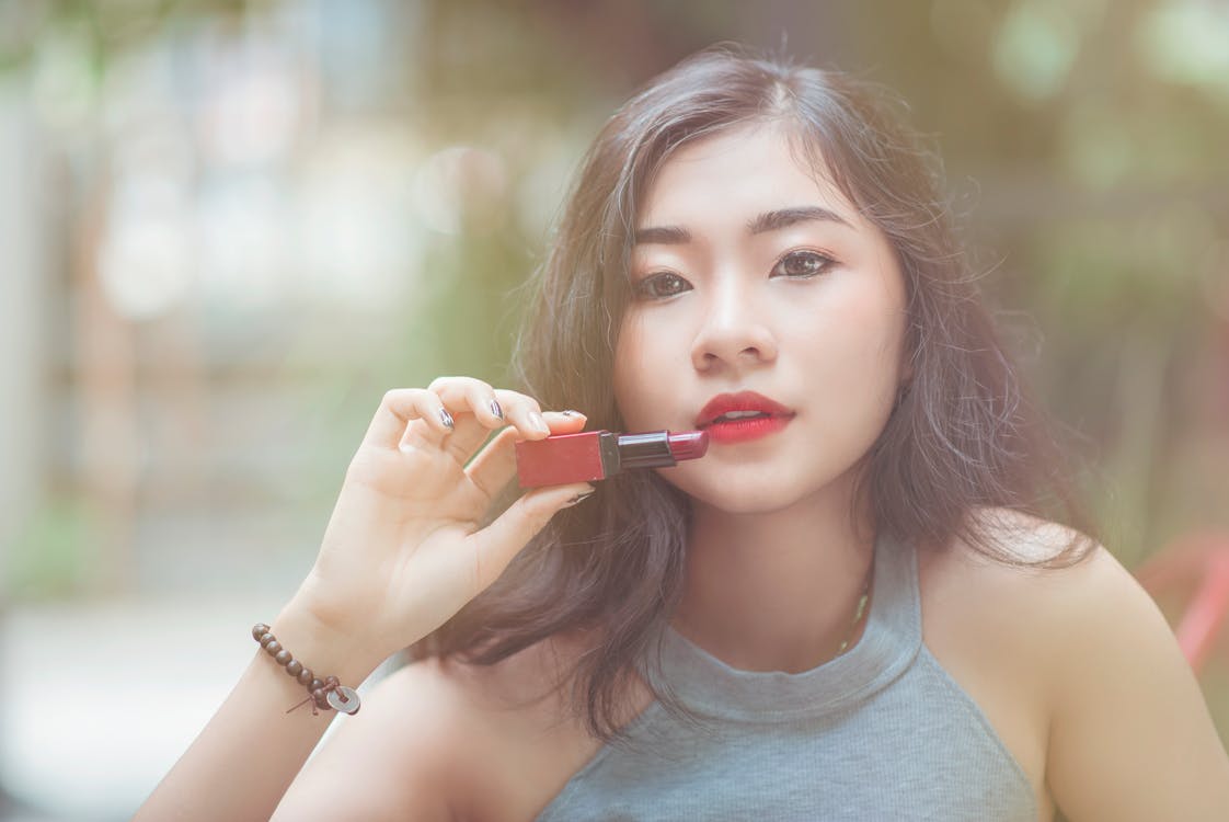 Woman Wearing Gray Halter-neckline Top Holding Red Lipstick