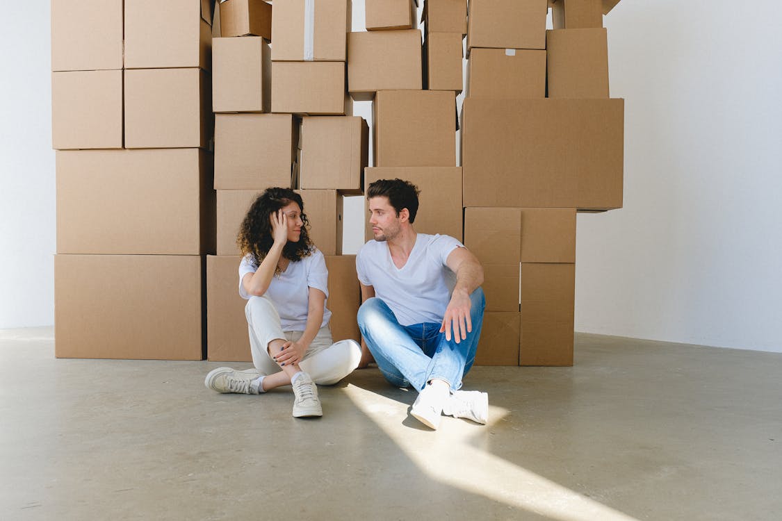 Free Couple speaking against pile of boxes in new house Stock Photo
