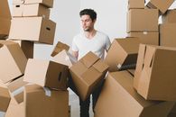 Man between stacks of cardboard boxes at home