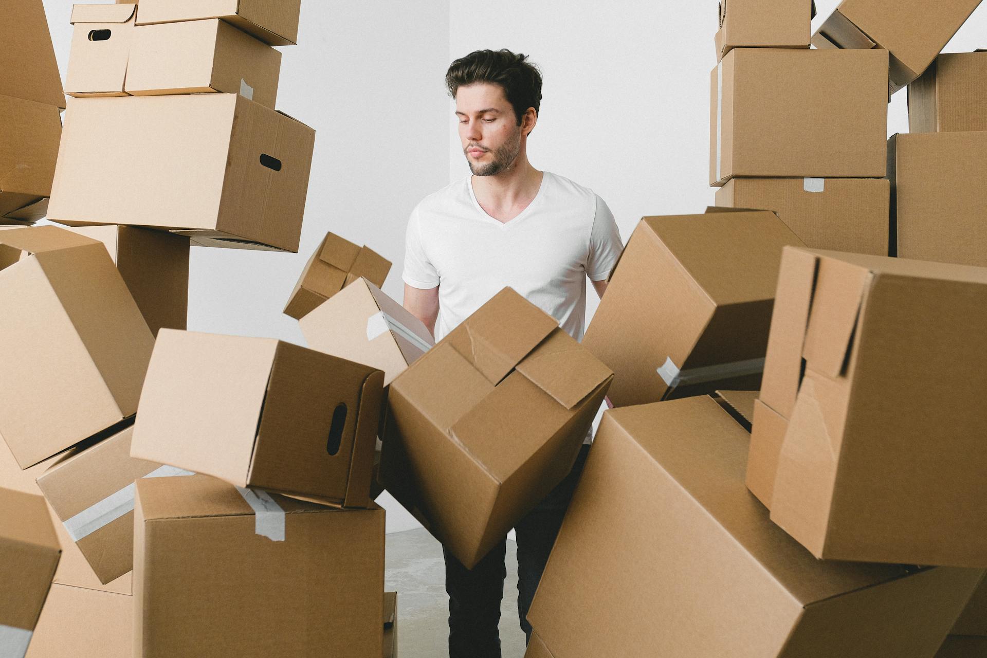 Man between stacks of cardboard boxes at home