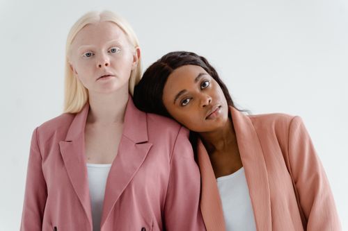 Free Portrait of two diverse women in pink suits representing modern business leadership and unity. Stock Photo