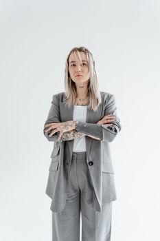 A confident woman with tattoos posing with arms crossed in a modern studio setting.
