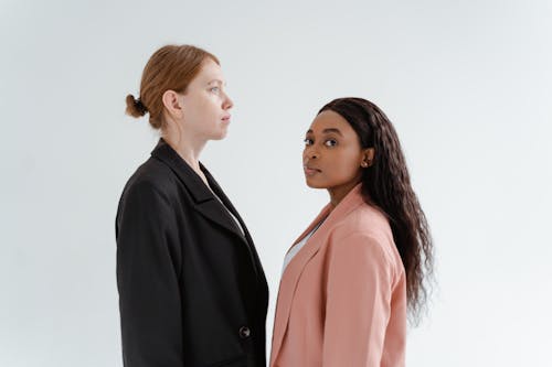 A Woman in Pink Blazer Standing Beside a Woman in Black Blazer