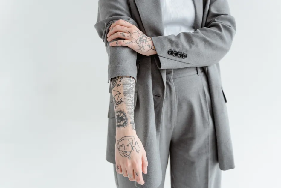 Tatouages fine line sur l'avant-bras et la main, portés avec une tenue élégante