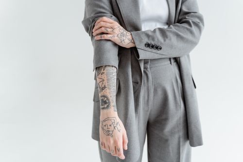 Free Close-up of a tattooed arm in a gray business suit, showcasing detailed ink designs. Stock Photo