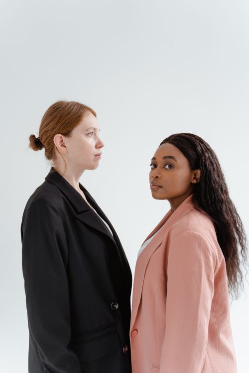 Free Elegant portrait of two women wearing fashionable blazers against a white background, exuding confidence. Stock Photo