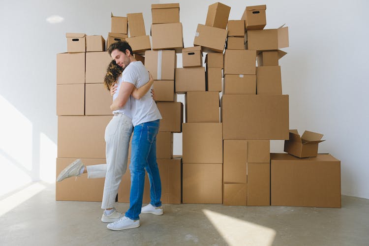 Man And Woman Hugging Near The Pile Of Boxes