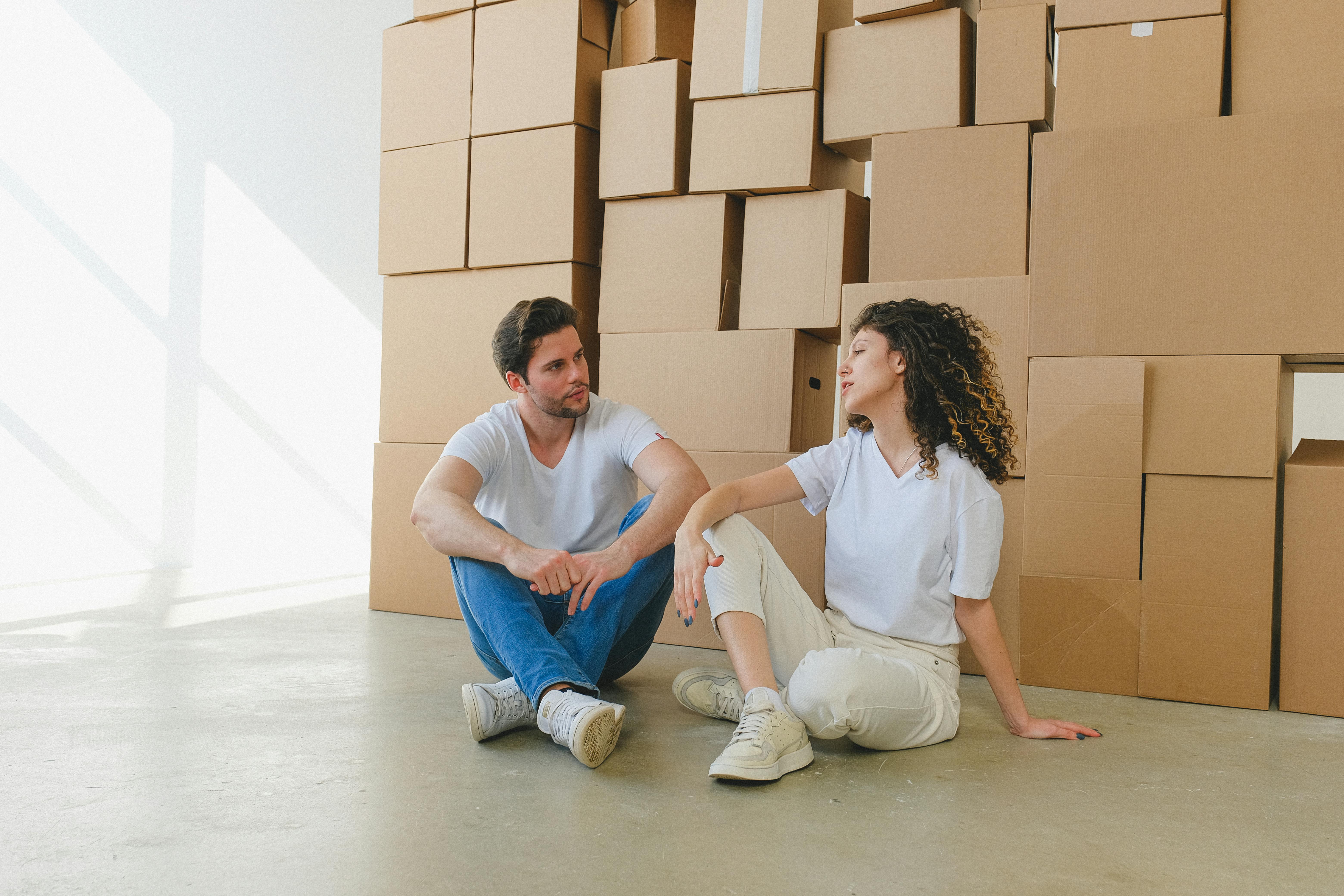 couple conversing against heaps of boxes during relocation
