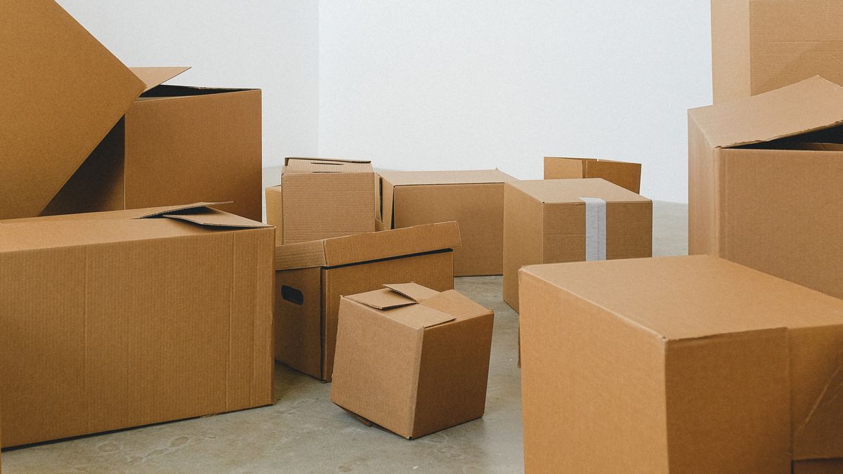 Cardboard moving boxes stacked on the floor of an empty room, the stage when relocation accommodation in Gloucester helps