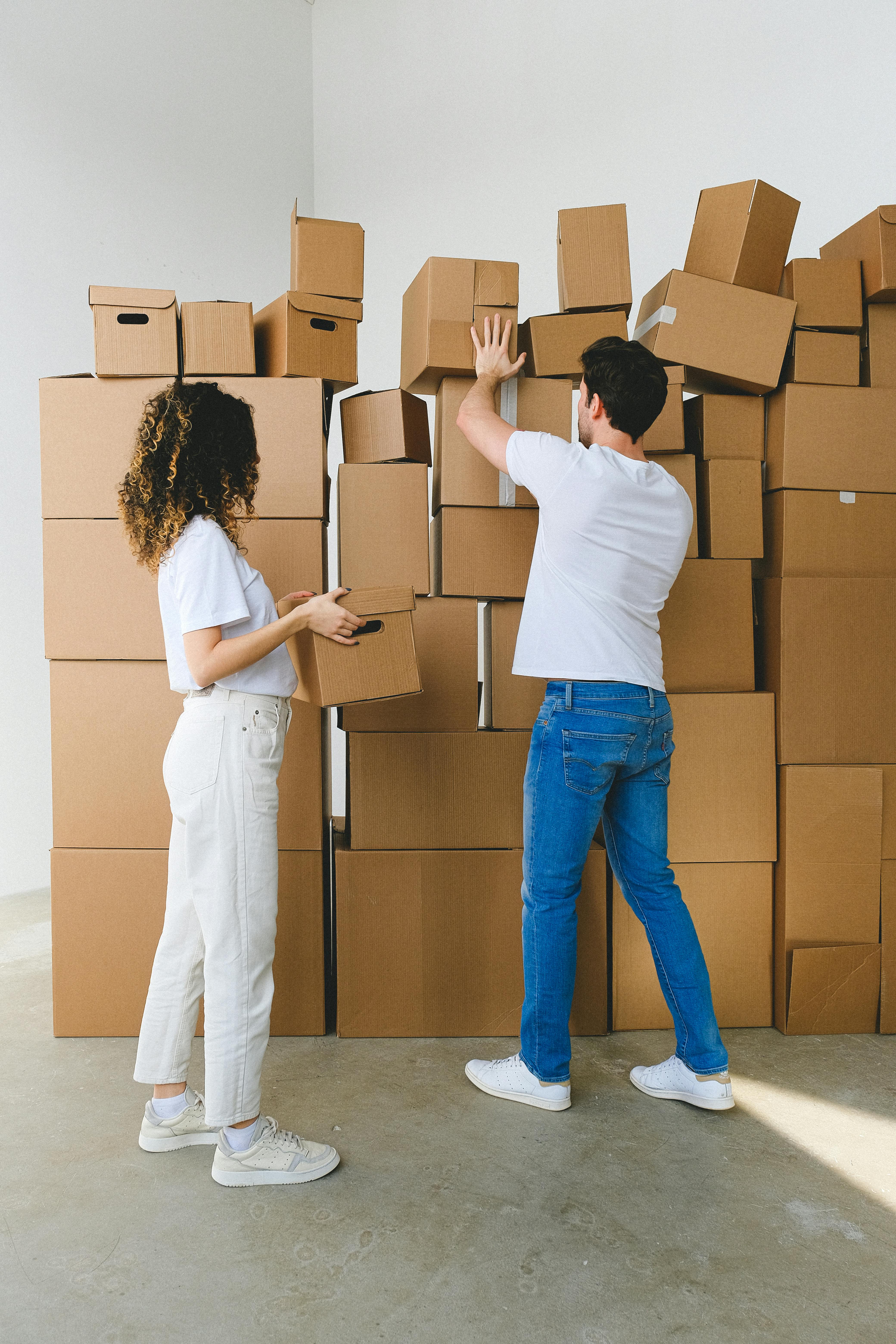 unrecognizable couple organizing cardboard boxes in new house