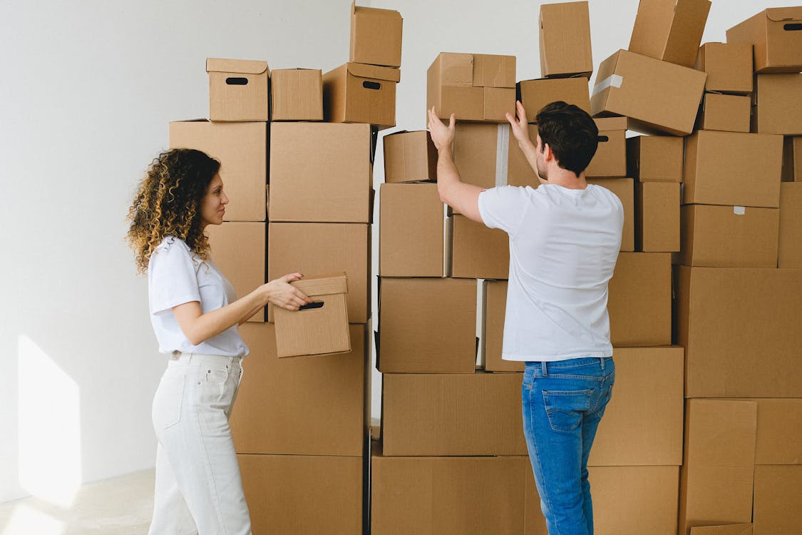 Young couple arranging stack of boxes after relocation