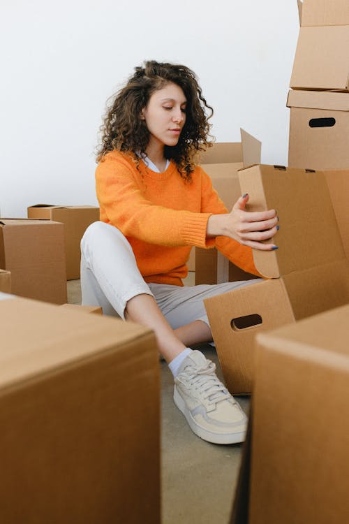 Young woman arranging cardboard boxes during relocation