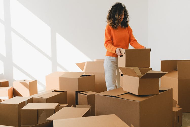 Serious Young Woman Packing Carton Box Before Moving In New Apartment