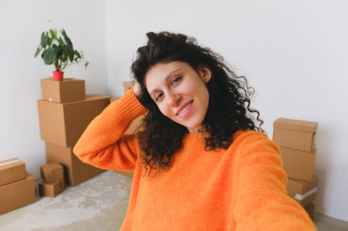 Content young woman smiling and taking selfie in new flat after relocation
