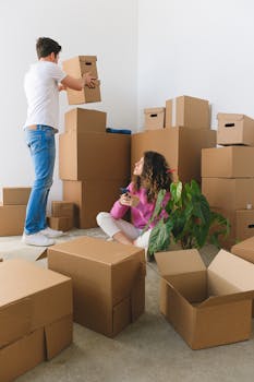 A young couple surrounded by cardboard boxes while moving into a new home.