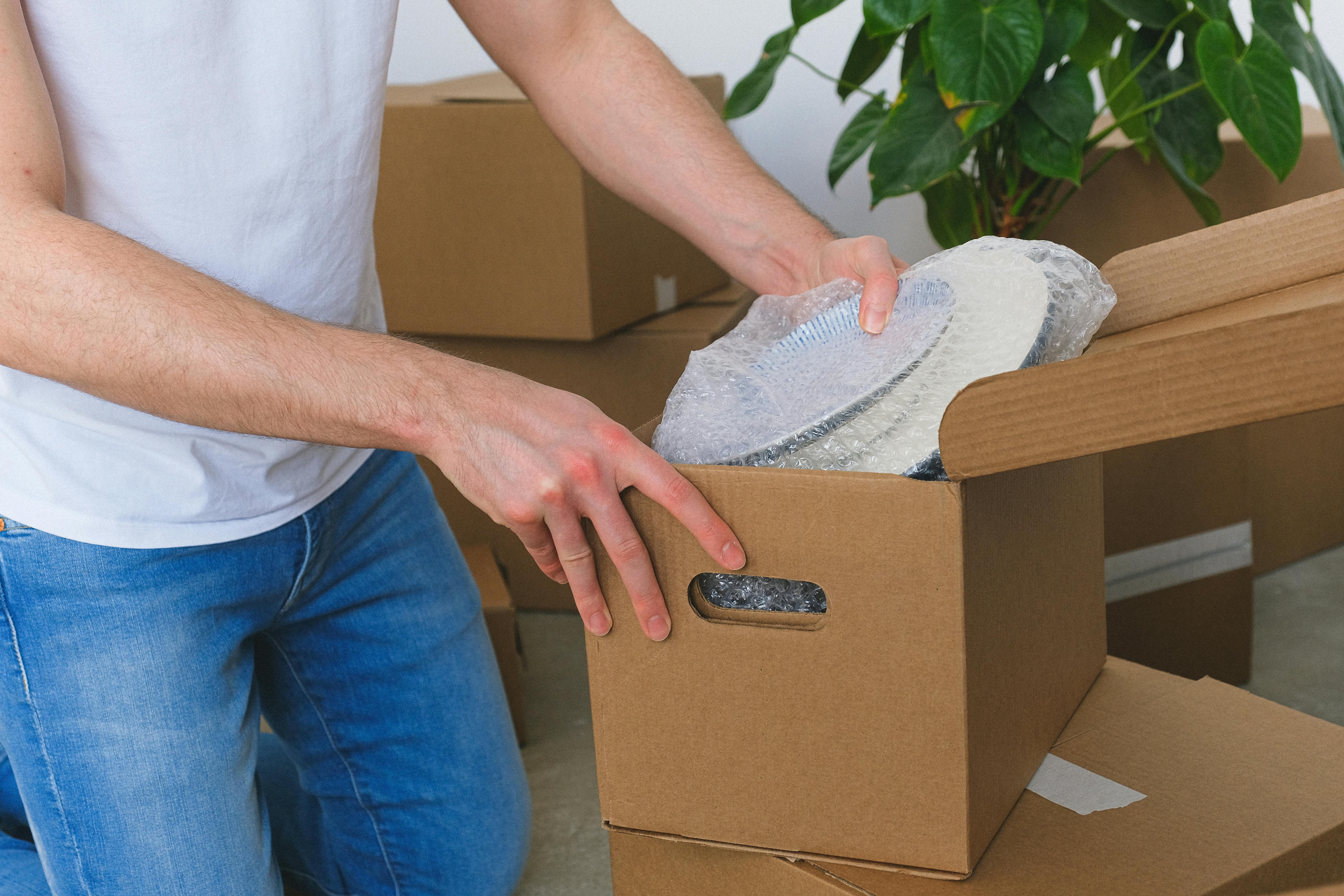 crop unrecognizable man packing belongings into cardboard box before relocation