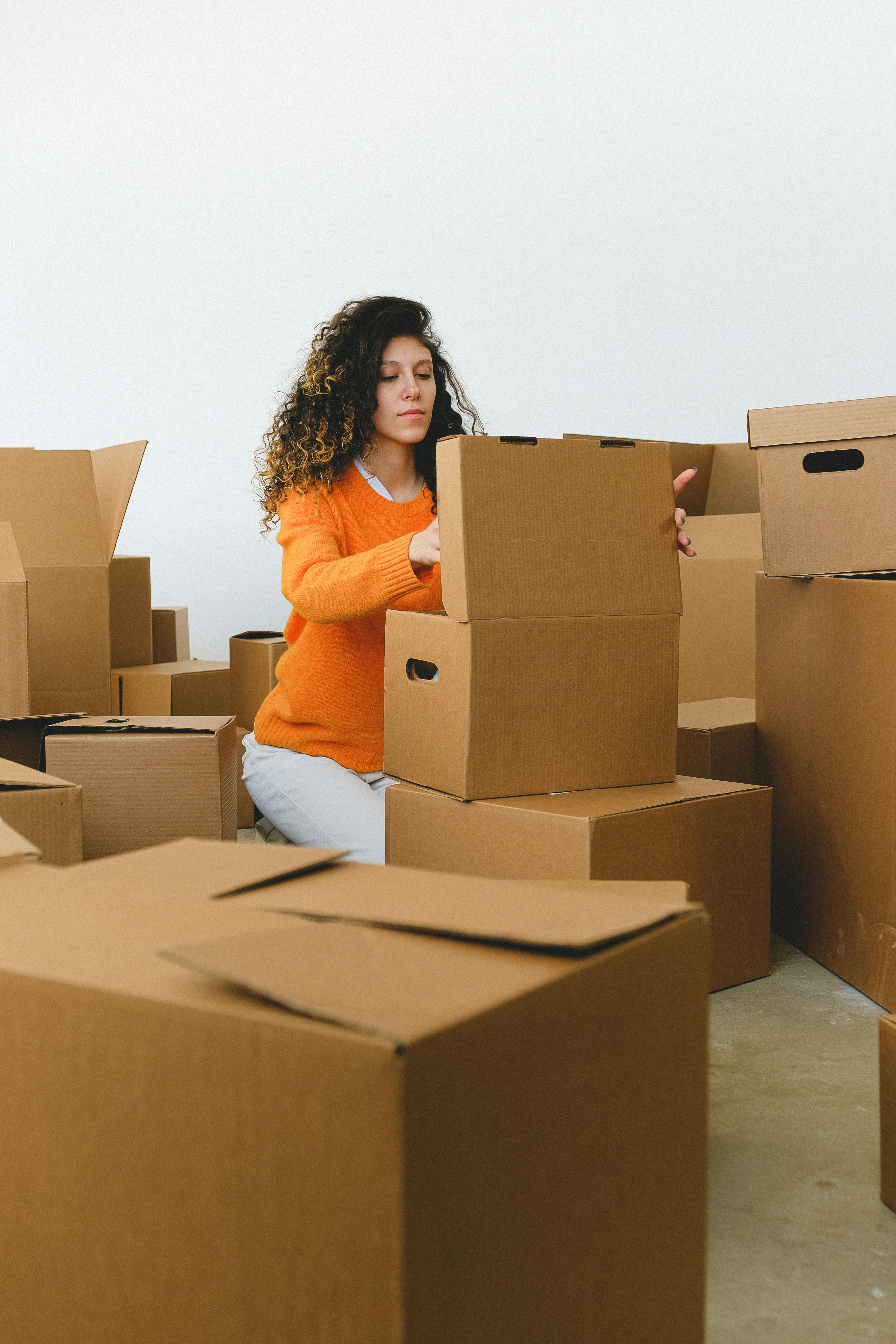 young relocating lady packing goods into boxes at home