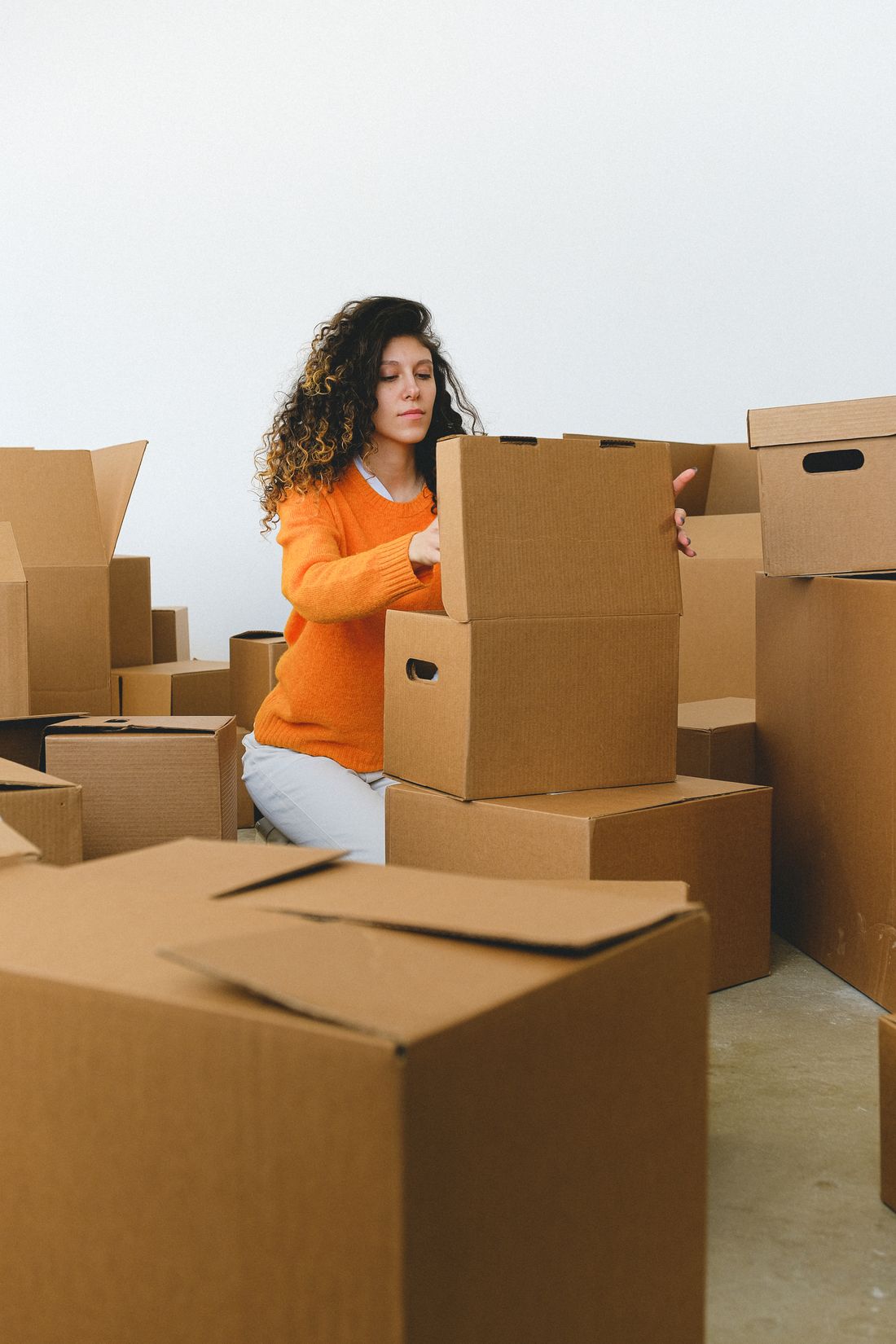 Relocating lady packing household goods into cardboard boxes at home in Dubai