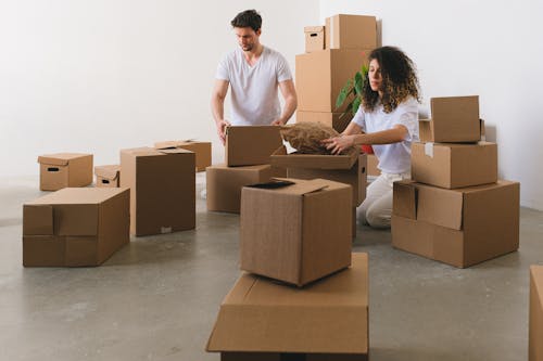 Focused young couple packing carton boxes before relocation