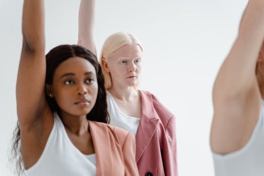 Diverse group of women in business attire holding arms up, symbolizing empowerment and unity.