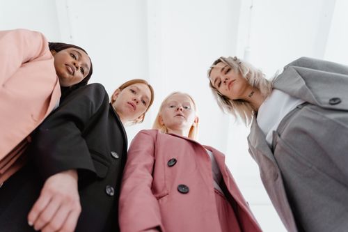 Free Four diverse women in professional business suits stand confidently looking down at the camera. Stock Photo
