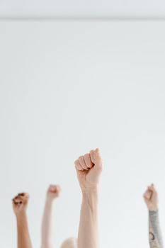 Group of diverse hands raising fists in unity against a plain white background.