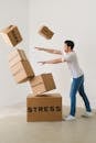 Full body of young man in sneakers and jeans pushing and falling boxes saying Work Problems Anxiety Stress and Deadline while fighting with problems