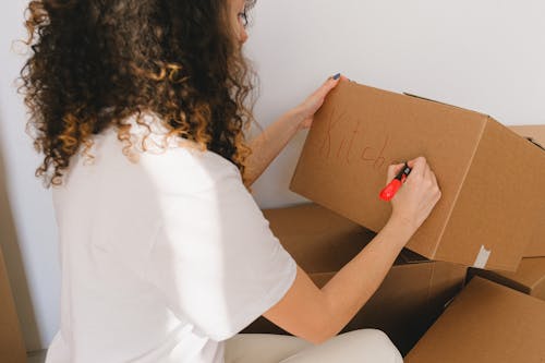 Free Woman in White Shirt Writing Label on Box Stock Photo