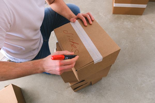 Person labeling a moving box with a marker