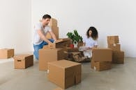 Couple unpacking carton boxes with household in new apartment