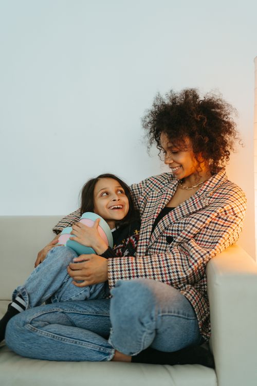 Free A mother and daughter smiling at each other, sitting on a sofa, showcasing warmth and connection. Stock Photo