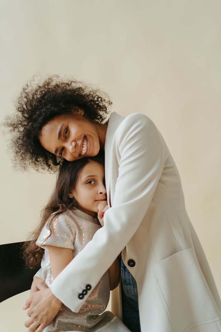 A Woman In White Blazer Embracing Her Daughter