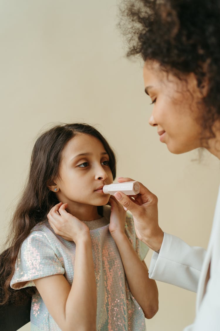 Mom Putting Lipstick On Daughter's Lips