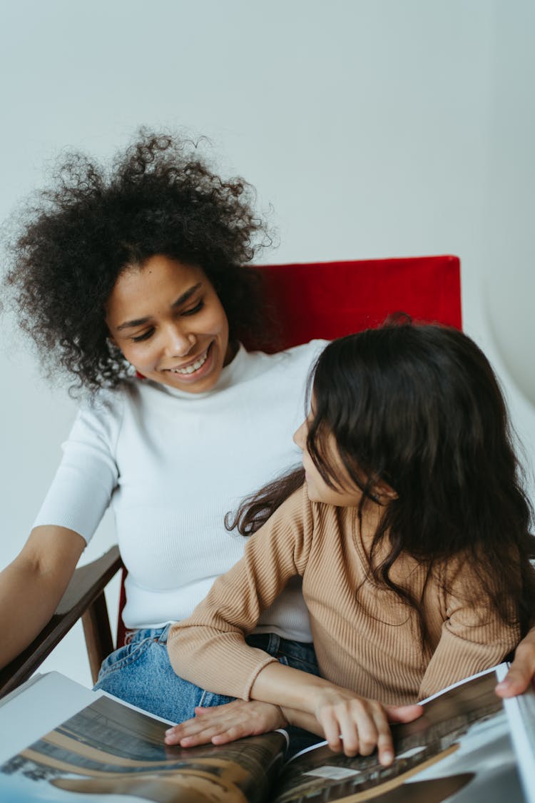 A Mother And Daughter Sitting On The Chair While Having Conversation