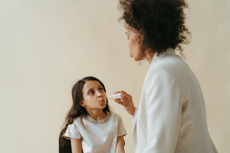 A Woman Putting Makeup On Her Daughter