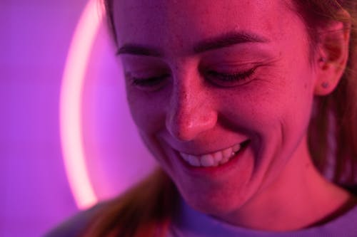Free Cheerful candid woman smiling near bright glowing violet lamp Stock Photo