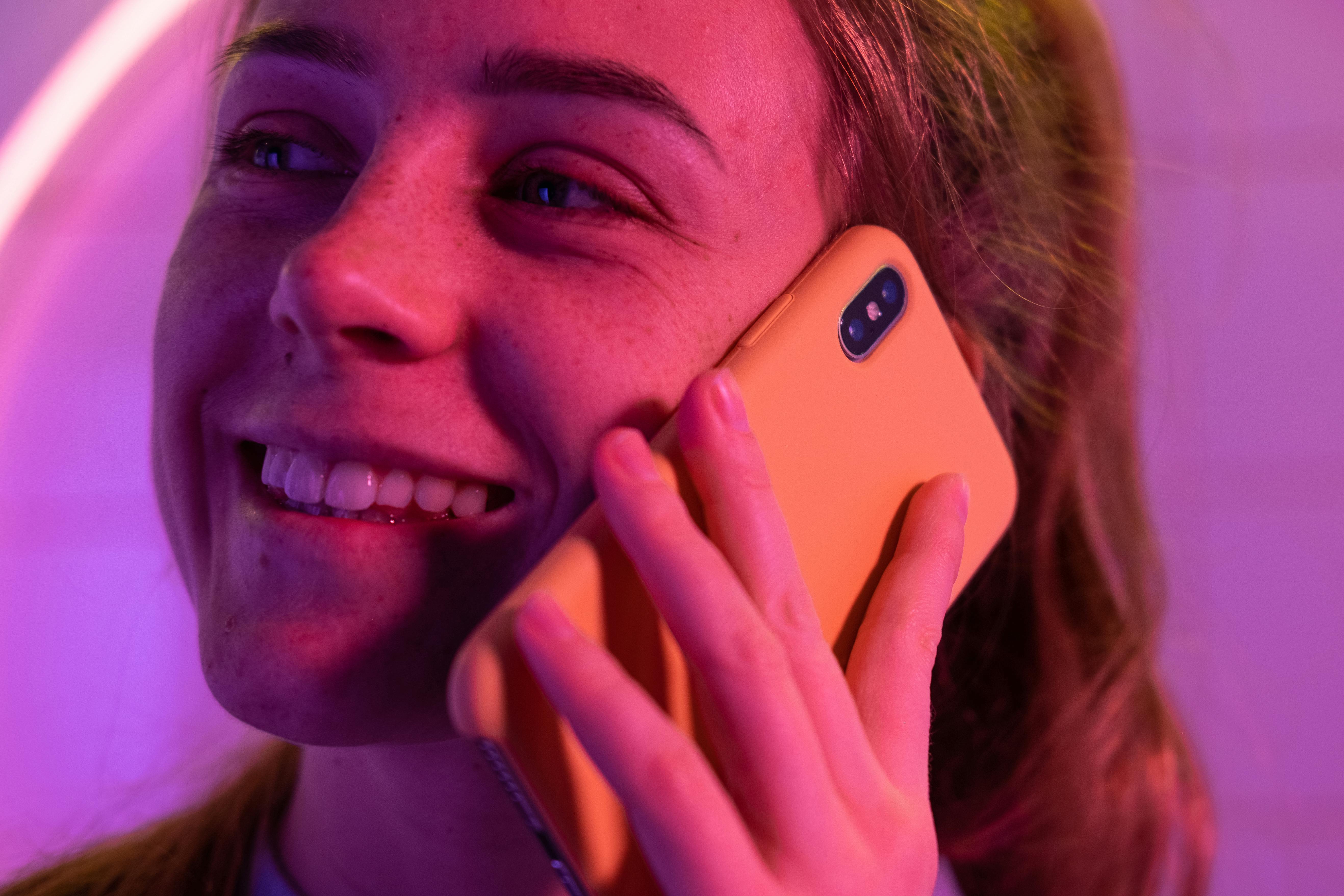 cheerful woman talking on smartphone in neon light